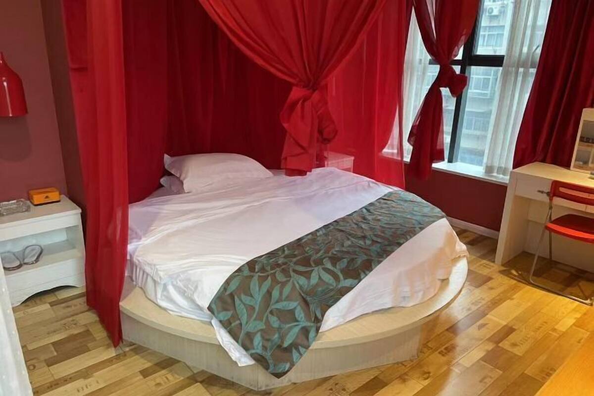 Een bed met hemelbed, een nachtkastje met een lamp en een raam met gordijnen.