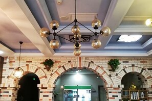 Een hotelinterieur met een bakstenen muur, gewelfde doorgangen en een kroonluchter.