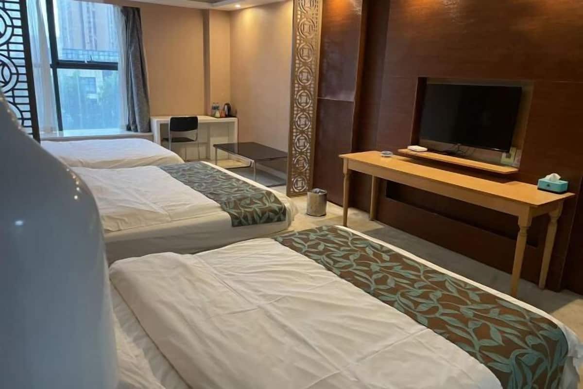 Een hotelkamer met twee bedden, een televisie, een bureau en een raam.