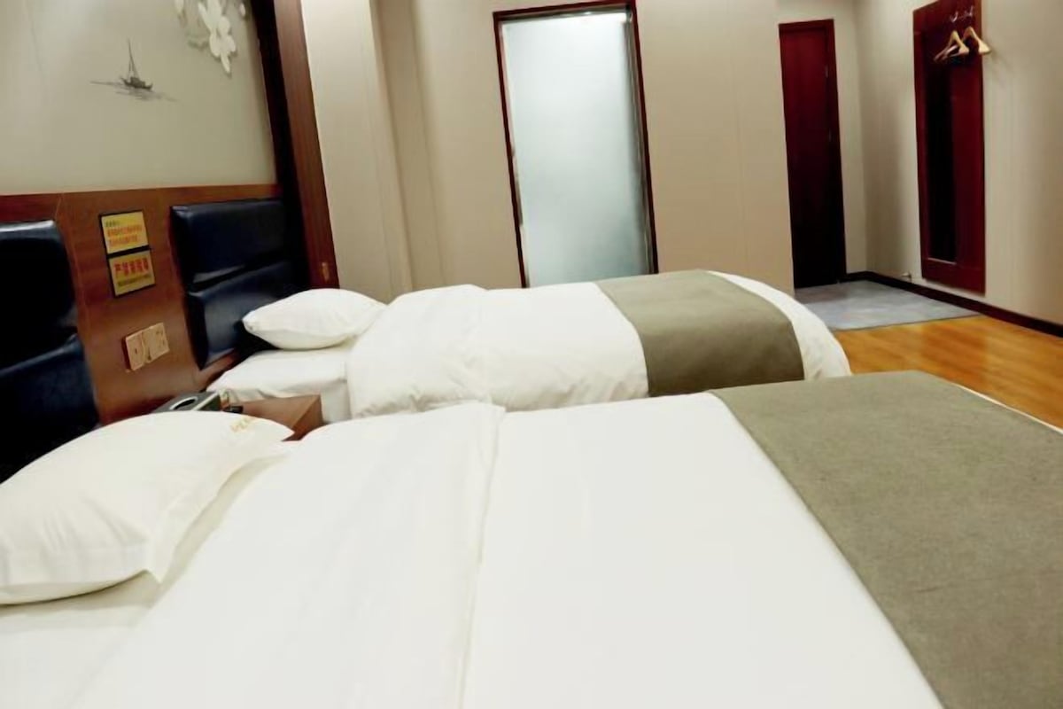 A hotel room with two beds, a wooden headboard, a mirror, and a door.