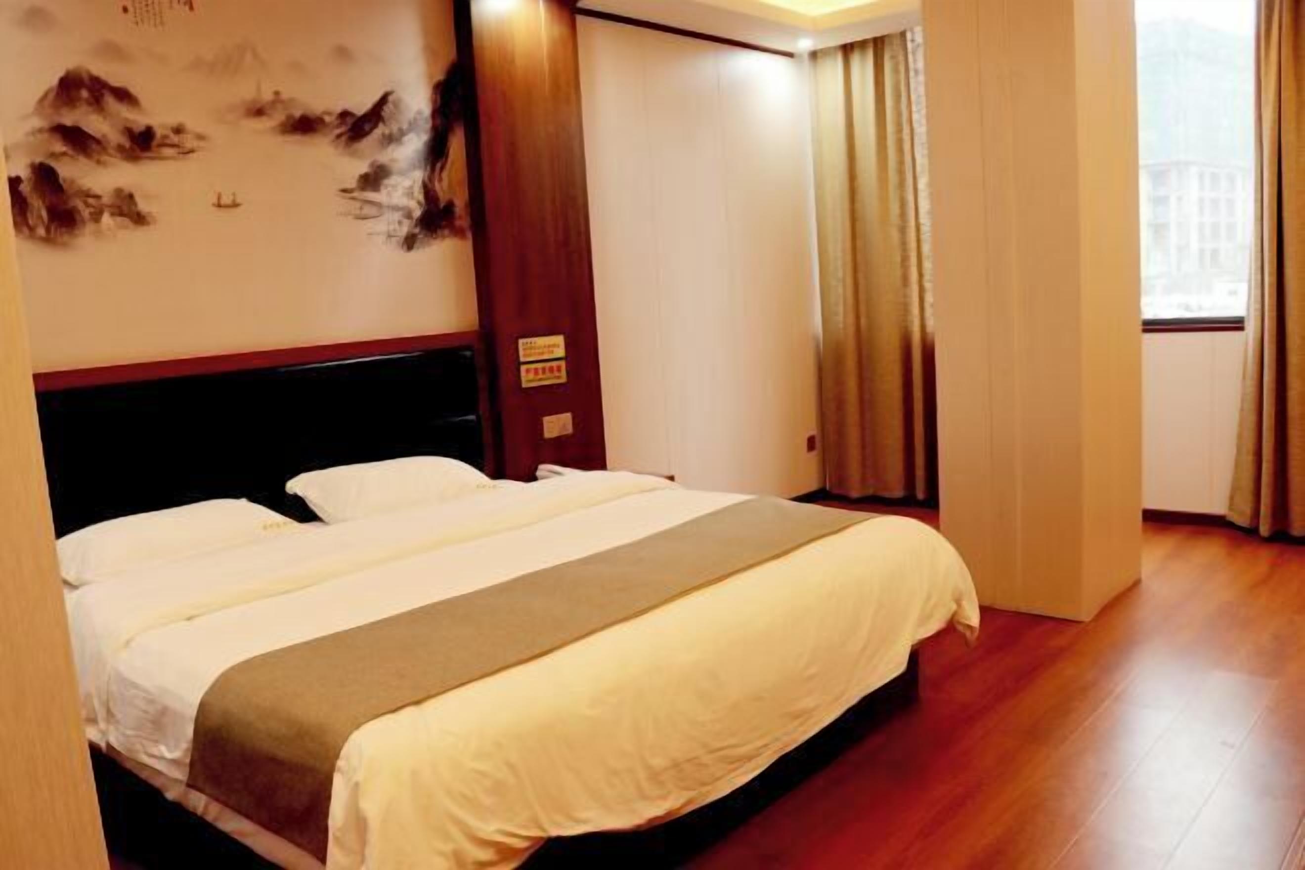 Una habitación de hotel con una cama grande, cabecera de madera, un mural en la pared y una ventana con cortinas.