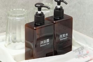 Two brown bottles with black pumps labeled "Shower Gel" and "Shampoo" on a white tray.
