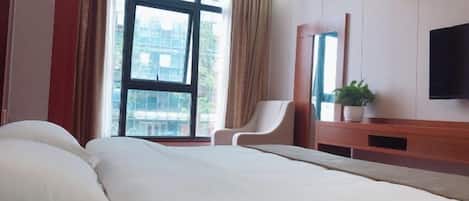 A hotel room with a large bed, a chair, a TV, and a window with curtains.