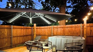 Een terras buiten met een tafel, stoelen, een barbecue en sfeerverlichting.