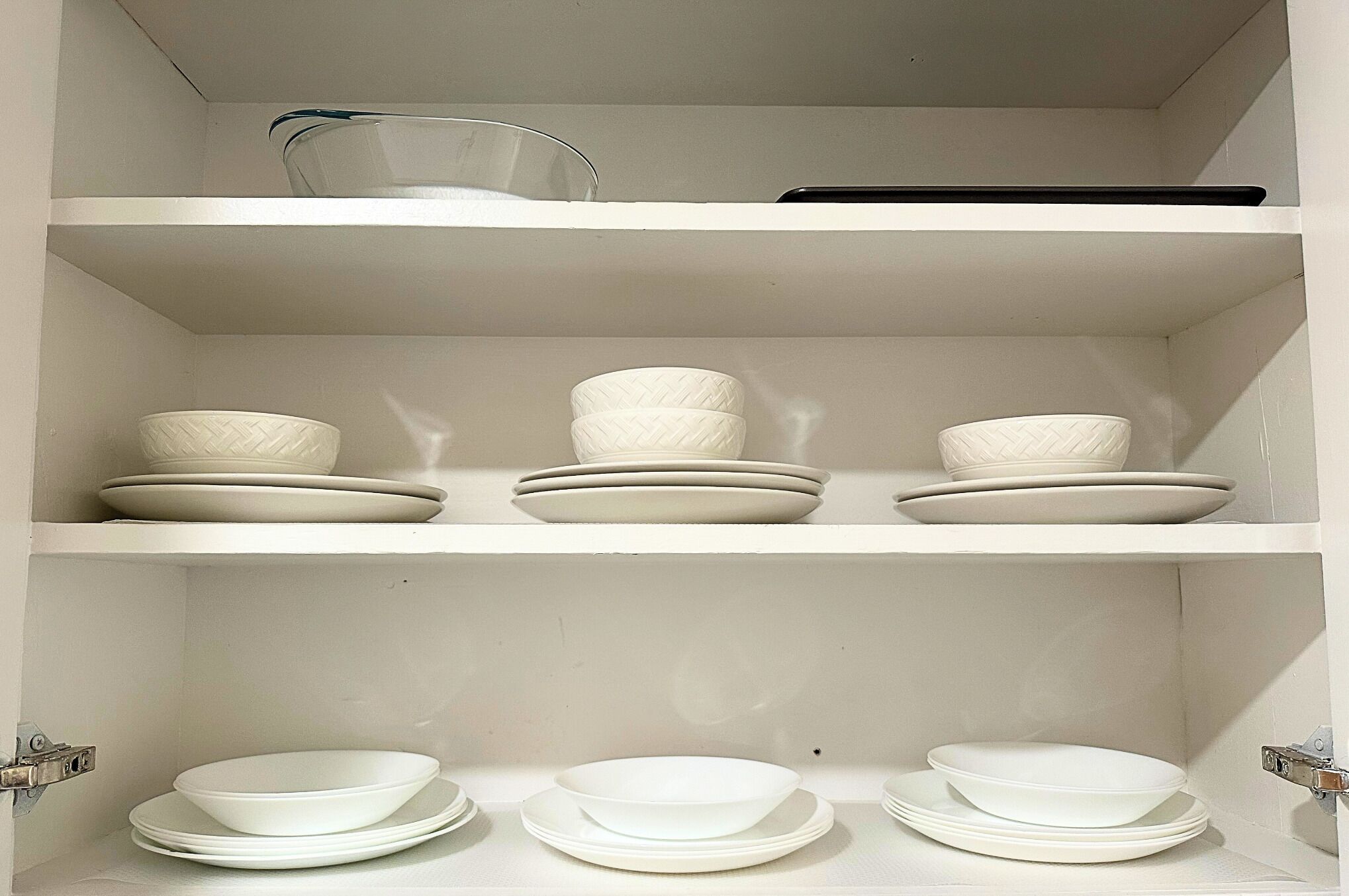 A white interior with shelves holding white bowls and plates.