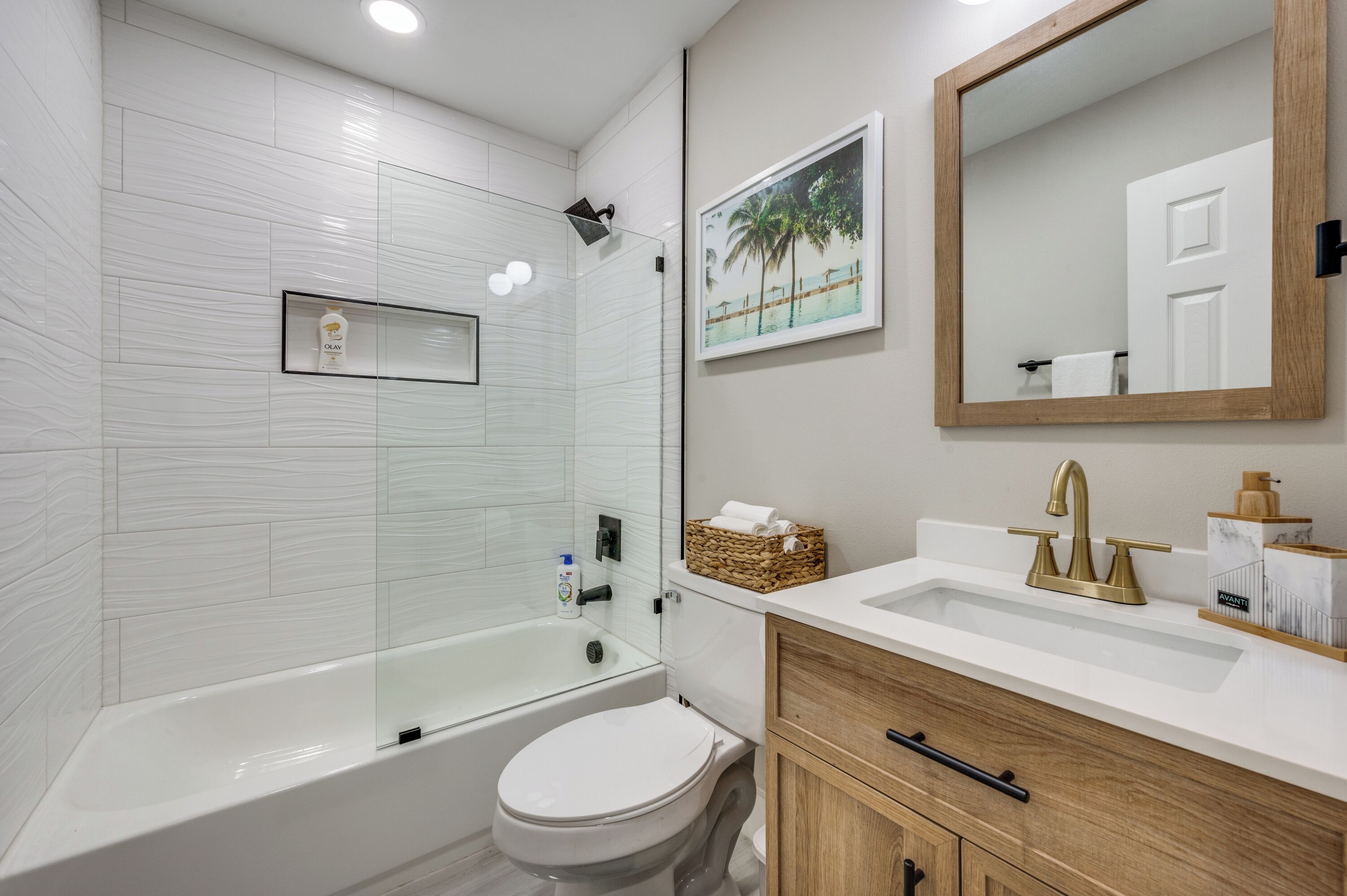 Een moderne badkamer met een douchecabine van glas, een wit toilet en een wastafel met spiegel en wastafelbak.