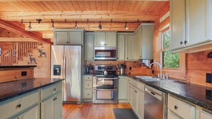 A modern kitchen with wooden cabinetry, stainless steel appliances, and a central island.