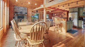 A wooden cabin interior with a dining area, kitchen, and a loft bedroom.