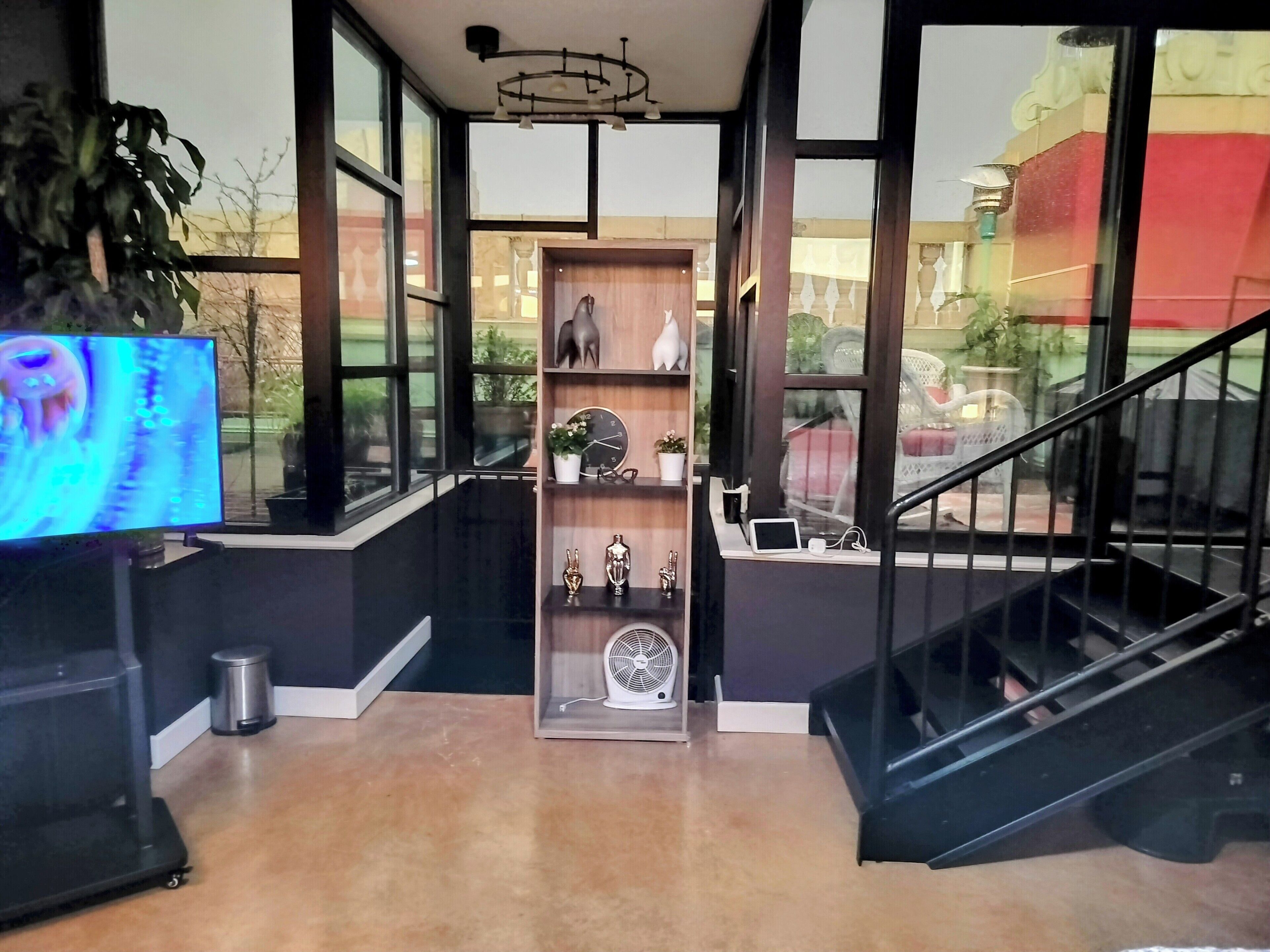 A modern interior with a large TV, a wooden shelf with decorative items, and a staircase.