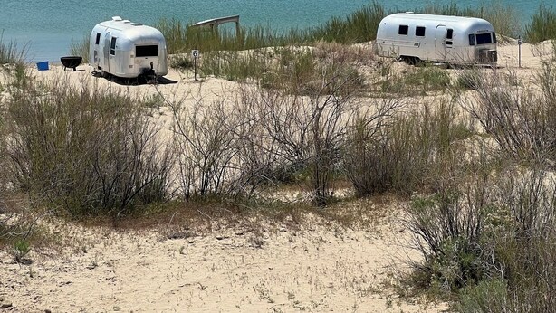 Two RVs parked by a lake with mountains in the background. - Firepit-Shade-Chairs-Dark Skies (Levan)