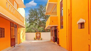 Um beco estreito com edifícios amarelos, um mural e vasos de plantas.