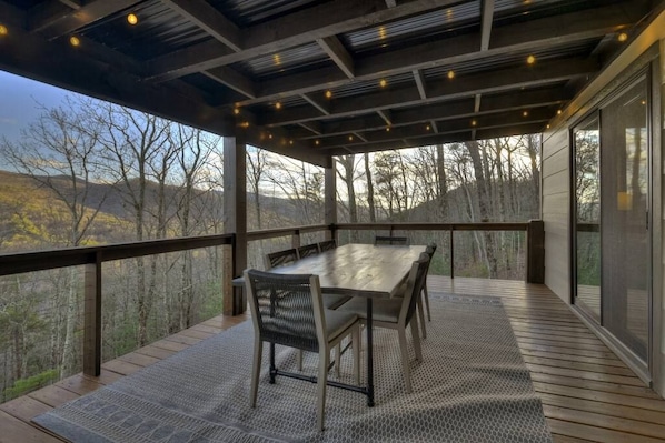 Une terrasse extérieure avec une table et des chaises, donnant sur un paysage boisé.