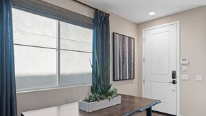 Ein modernes Zimmer mit großem Fenster, einer weißen Tür und einer Sitzbank.