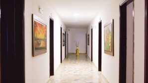 A hallway with patterned floor tiles, framed artwork on the walls, and doors leading to rooms.
