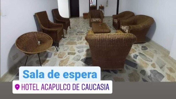 A waiting room with wicker furniture, a television, and a stone floor.