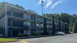 A multi-story hotel with a parking lot in front. - Hilltop Inn (Conley)