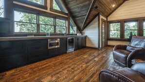 A modern kitchen with dark cabinetry, a built-in oven, and a large window overlooking greenery. - Stag's Manor|Stunning Mtn Views|Game Room|Hot Tub (Morganton)
