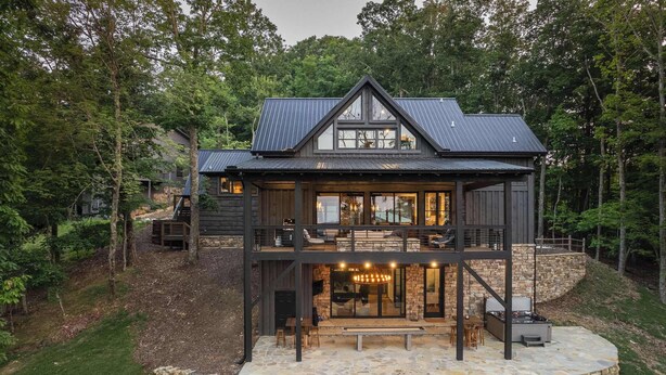 A two-story wooden cabin with a stone foundation, large windows, and a balcony. - Stag's Manor|Stunning Mtn Views|Game Room|Hot Tub (Morganton)