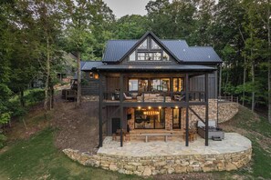 Een houten chalet met twee verdiepingen, een stenen fundering, grote ramen en een balkon.