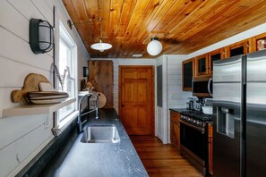 A compact kitchen with a wooden ceiling, a stainless steel refrigerator, and a built-in oven. - Holden Haus | Creekside Cabin + Hot Tub + Dogs (Ellijay)