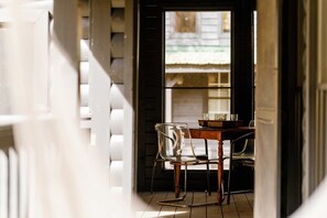 A hallway with a wooden table and chairs, a window with a view of a building, and a staircase with white railings.
