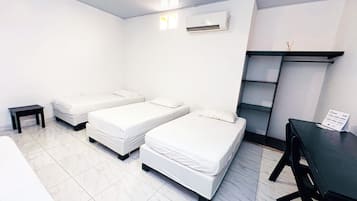 Una habitación con dos camas individuales, una mesita, un escritorio y una estantería.