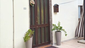 A door with a decorative wreath, a mailbox, and two potted plants. - Apartment in Matera near Historic Center (Matera)