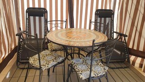 A round table with a mosaic tile top surrounded by four chairs with patterned cushions. - Apartment in Matera near Historic Center (Matera)
