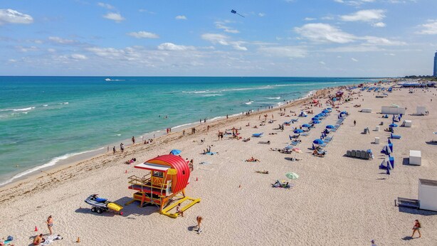 Une plage avec un poste de surveillance pour les sauveteurs, des parasols et des chaises de plage.