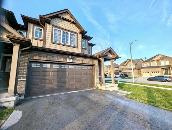 A two-story house with a garage, a covered porch, and a well-maintained lawn. - Niagara Getaway! 6 bedrooms , 4.5 baths. Up to 12 guests. Gameroom in Garage.  (Thorold)