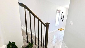 A staircase with wooden balusters leading to a landing. - Niagara Getaway! 6 bedrooms , 4.5 baths. Up to 12 guests. Gameroom in Garage.  (Thorold)