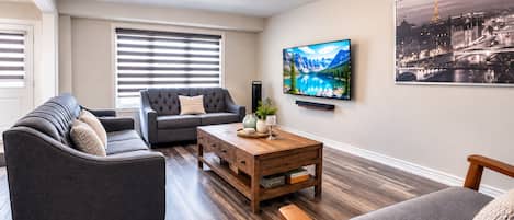 Una sala de estar con un sofá, una mesa de centro y un televisor montado en la pared.