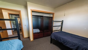 Une chambre avec deux lits simples, une armoire et un miroir.