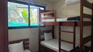 Habitación con literas y vista a una piscina y follaje verde.