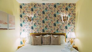 A hotel room with a bed, two bedside lamps, a headboard, and a patterned wallpaper. - NEW!! The Coop I Pettigrew Adventures in Midtown - Located in Cooper Young  (Memphis)