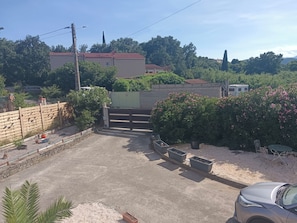 Un área de estacionamiento con entrada porticada, plantas en macetas y un automóvil.