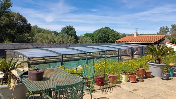 Een dakbalkon met zwembad, een overdekte zithoek en potplanten.