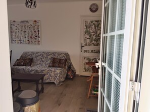 Una sala de estar con un sofá estampado, una mesita y una puerta decorada con un estampado tropical.
