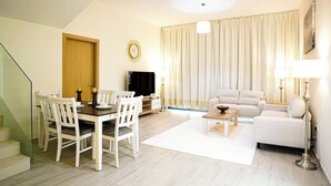 Una sala de estar moderna con comedor, un sofá, una mesa de centro y un televisor.
