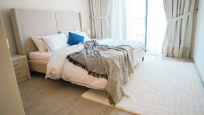 Un dormitorio con cama, mesita de noche y ventana con cortinas.