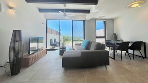 Un salón espacioso con un sofá, una mesa de comedor con sillas, un televisor y un ventilador de techo.