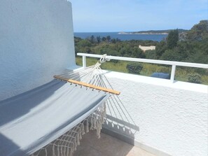 A hammock on a balcony with a view of the sea and greenery. - Joli Appartement à Cargèse Avec vue sur mer et Coucher de Soleil (Cargèse)