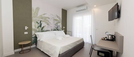 A modern bedroom with a bed, a desk, a chair, and a television.