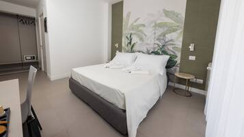 Una habitación de hotel moderna con una cama grande, una mesita redonda y una planta en la pared.