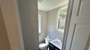 Une salle de bain avec des toilettes, un lavabo et un miroir.