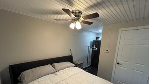 Une chambre à coucher avec un lit, un ventilateur de plafond et une porte.