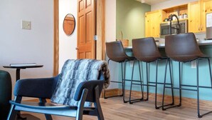 A modern kitchen with wooden cabinets, a microwave, and a bar stool area.