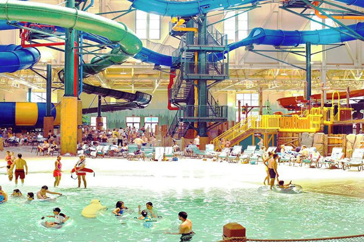 Parque acuático interior con múltiples toboganes y piscinas.