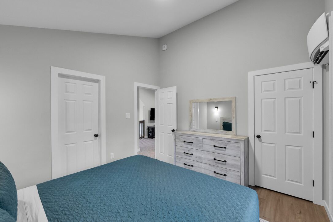 Une chambre à coucher avec un lit, une commode, un miroir et deux portes.