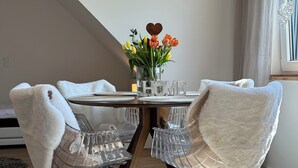 A dining area with a round table, clear chairs, a 'HOME' sign, and a vase with flowers. - Neue , Moderne , Lichtdurchflutete Ferienwohnung 🌸 (Hallerndorf)